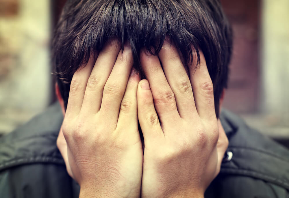 young boy holding head in hands